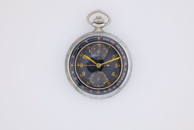 an old pocket watch on a white surface with a yellow second hand