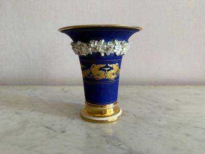a blue vase with gold decoration on it on a table