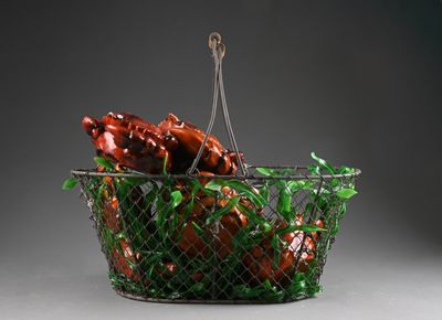 un panier en fil de fer rempli de viande et de légumes, posé sur une surface grise
