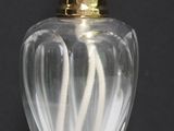 un vase en verre avec un couvercle doré posé sur une table blanche