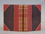 deux livres à la couverture rouge et aux bords dorés posés sur une surface blanche
