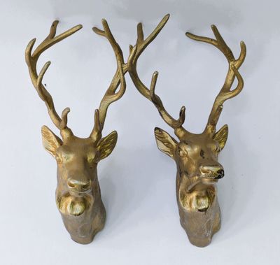 une paire de têtes de cerfs en laiton avec des bois, sur fond blanc