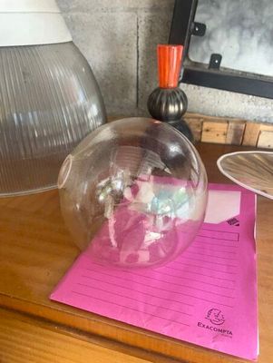 une boule de verre posée sur un bureau, à côté d'un bloc-notes et d'une lampe