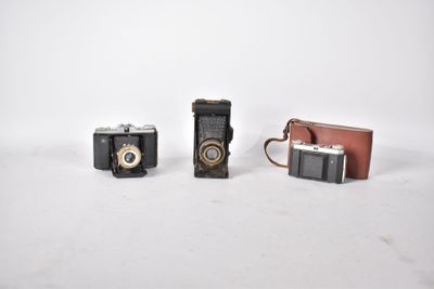 deux vieux appareils photo posés l'un à côté de l'autre sur une surface blanche