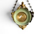 a gold and green clock hanging on a chain