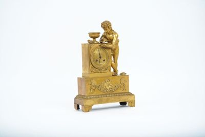 une horloge en or surmontée d'une statue représentant un homme assis