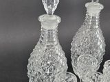 four glass bottles and a glass stopper on a table