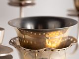 a silver candle holder with cups and saucers on it