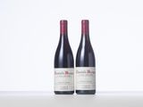 two bottles of red wine sitting on top of a white table