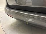 the rear end of a silver car with scratches on it ' s bumper