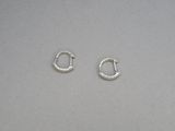 une paire de petites boucles d'oreilles en argent en forme d'anneaux posées sur une surface grise