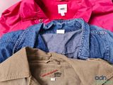 several different colored shirts stacked on top of each other on a table