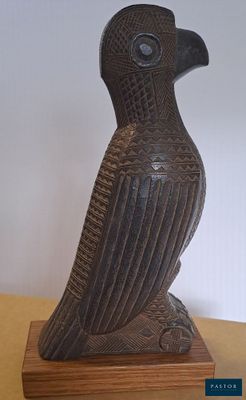 une statue représentant un oiseau perché sur un socle en bois