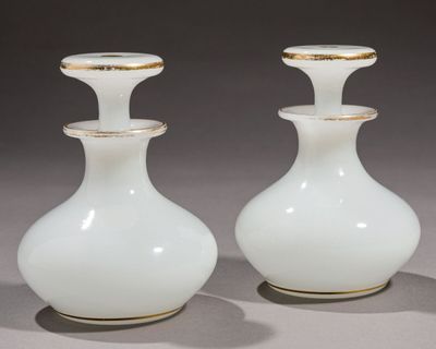 une paire de vases blancs aux bords dorés posés sur une surface grise