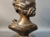bronze bust of a woman with a bird perched on her head