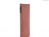 an old book with a brown cover sitting on top of a white surface