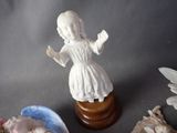 a figurine of a girl in a white dress next to other figurines