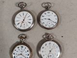four different types of pocket watches are displayed on a table