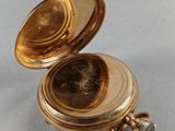a small gold pocket watch sitting on a table
