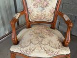 une vieille chaise avec un dossier et des accoudoirs tapissés de fleurs