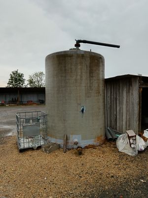 un grand réservoir métallique posé au milieu d'un champ de terre battue