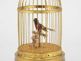 un oiseau doré dans une cage, sur fond blanc