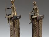 pair of bronze figurines of a woman sitting on top of a table