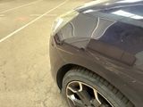 a black car parked in a parking lot with other cars in the background