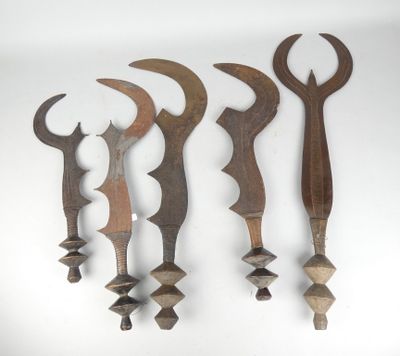 cinq outils en bois sont alignés contre un mur blanc