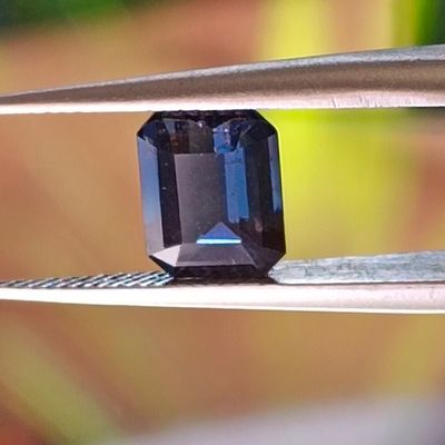 un gros plan d'un diamant bleu en train d'être taillé à l'aide d'une paire de pinces