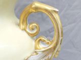 a white vase with a gold leaf decoration on it