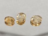 three yellow sapphires on a white surface