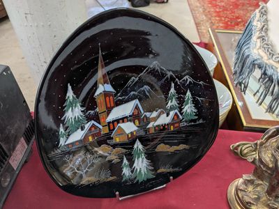 une assiette noire sur laquelle est représentée une maison