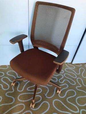 une photo d'une chaise de bureau marron posée sur un tapis dans une pièce