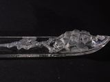 a glass spoon with ice in it on a black surface