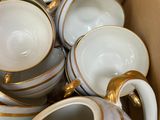 a box full of white and gold coffee cups and saucers