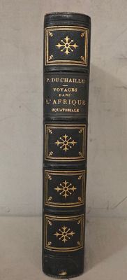 un vieux livre noir aux tranches dorées posé sur une table