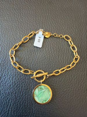 un bracelet en or orné d'une breloque en forme de feuille verte