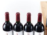 three bottles of red wine are lined up on a wooden box