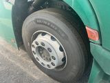 a green truck with a flat tire parked on the street