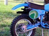 a blue dirt bike that is parked in the grass