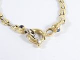 a close up of a gold chain bracelet with a blue stone