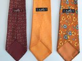 three different colored ties are lined up on a white surface