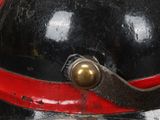 a black and red helmet with a gold button on it