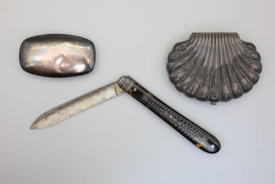 a knife, a shell, and a pocket knife on a table