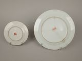 two white plates with red designs on them sitting next to each other