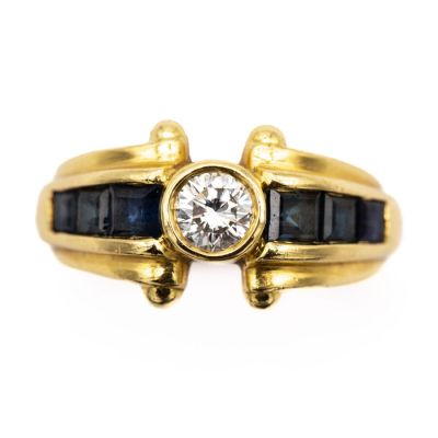a close up of a gold ring with a diamond and sapphire stones