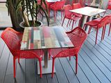 tables and chairs on a deck with a potted plant on the table
