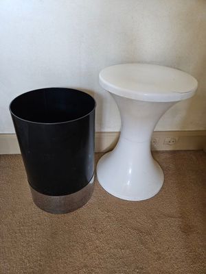 a black and white trash can next to a white stool