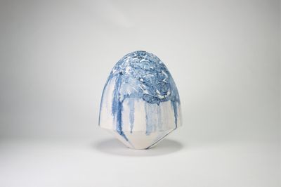 un vase bleu et blanc posé sur une surface blanche
